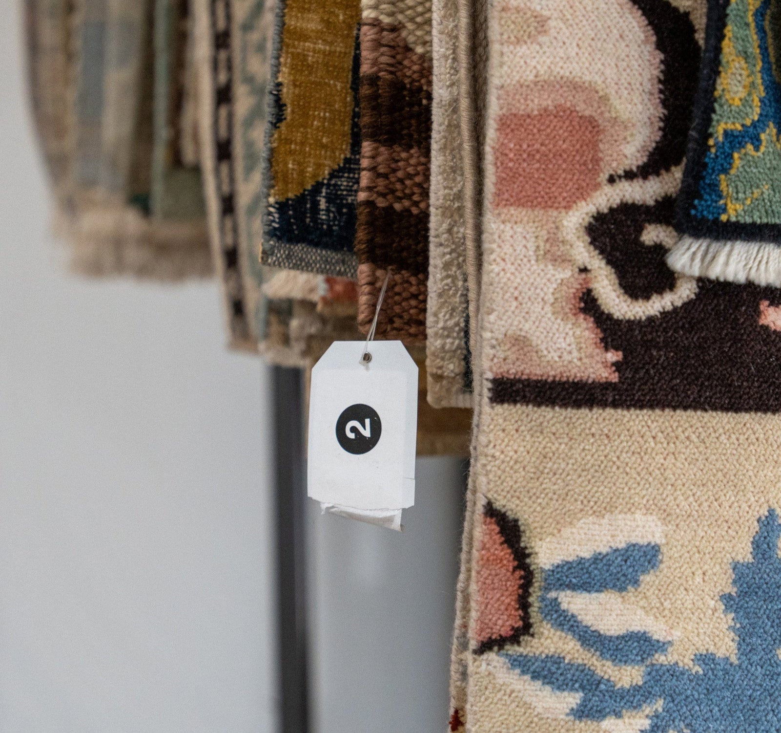 Close-up of patterned rugs with a tag on a white background
